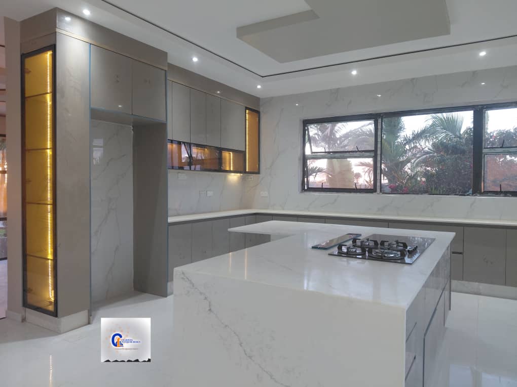 Open-plan grey kitchen with a marble island, gas hob and garden palms beyond the window