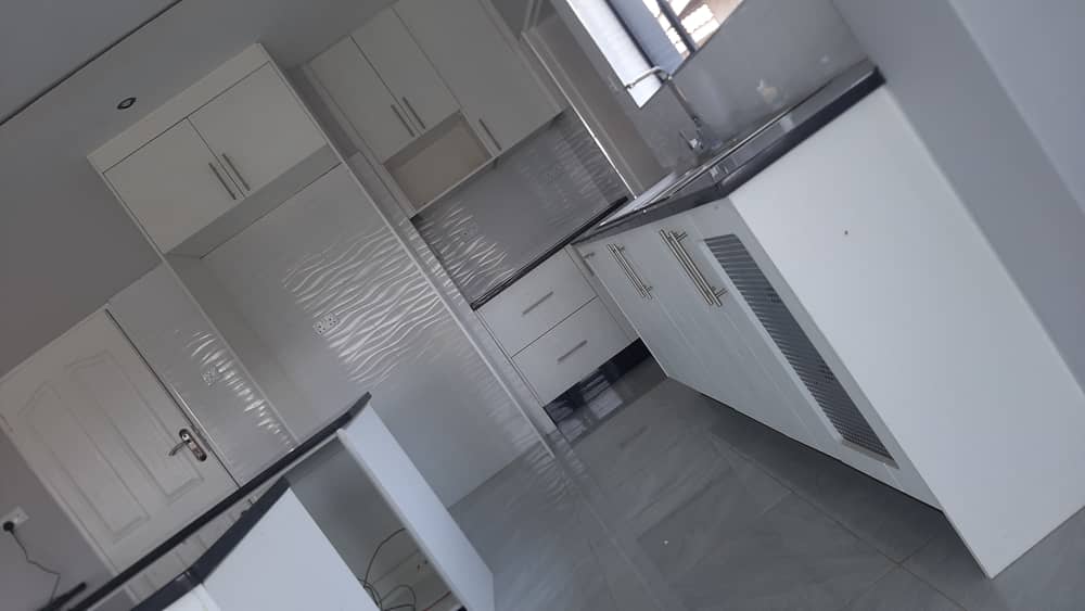 White kitchen run with dark stone worktops and high-level storage