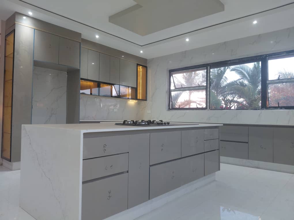 Handleless grey kitchen island with integrated hob and marble splashback
