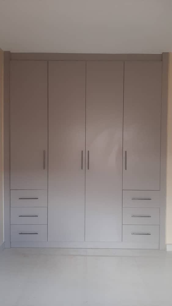 Handleless taupe fitted wardrobe with flanking drawer stacks