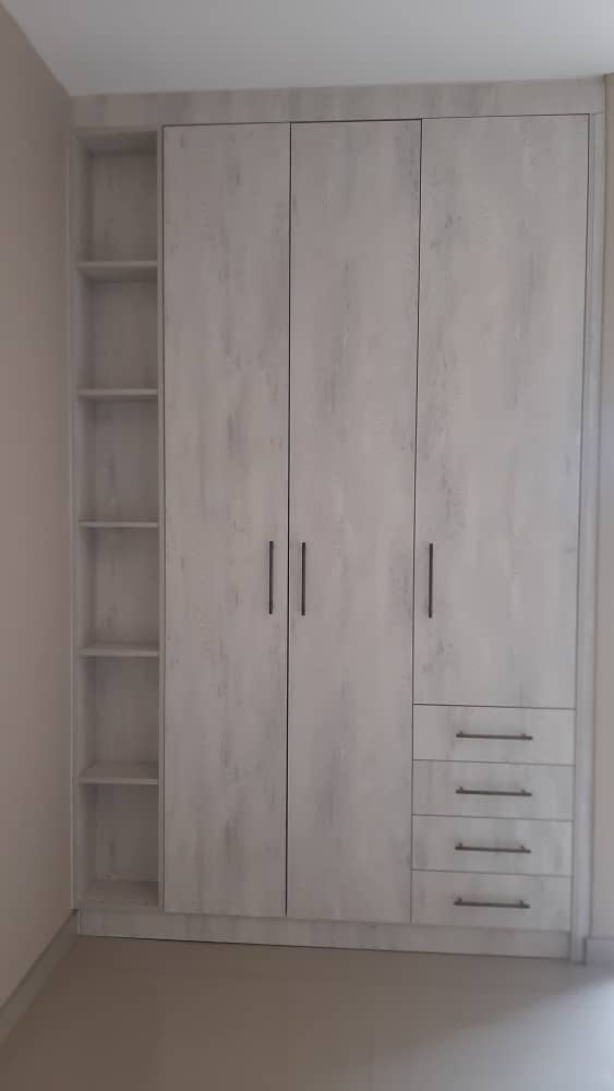 Pale oak-effect fitted wardrobe with open side shelves and three drawers