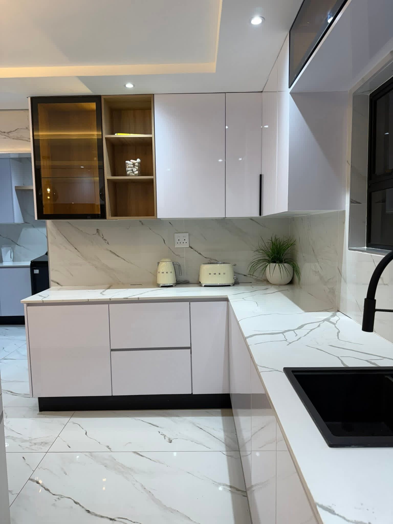 Close detail of white cabinetry, oak open shelf, marble splashback and black mixer tap