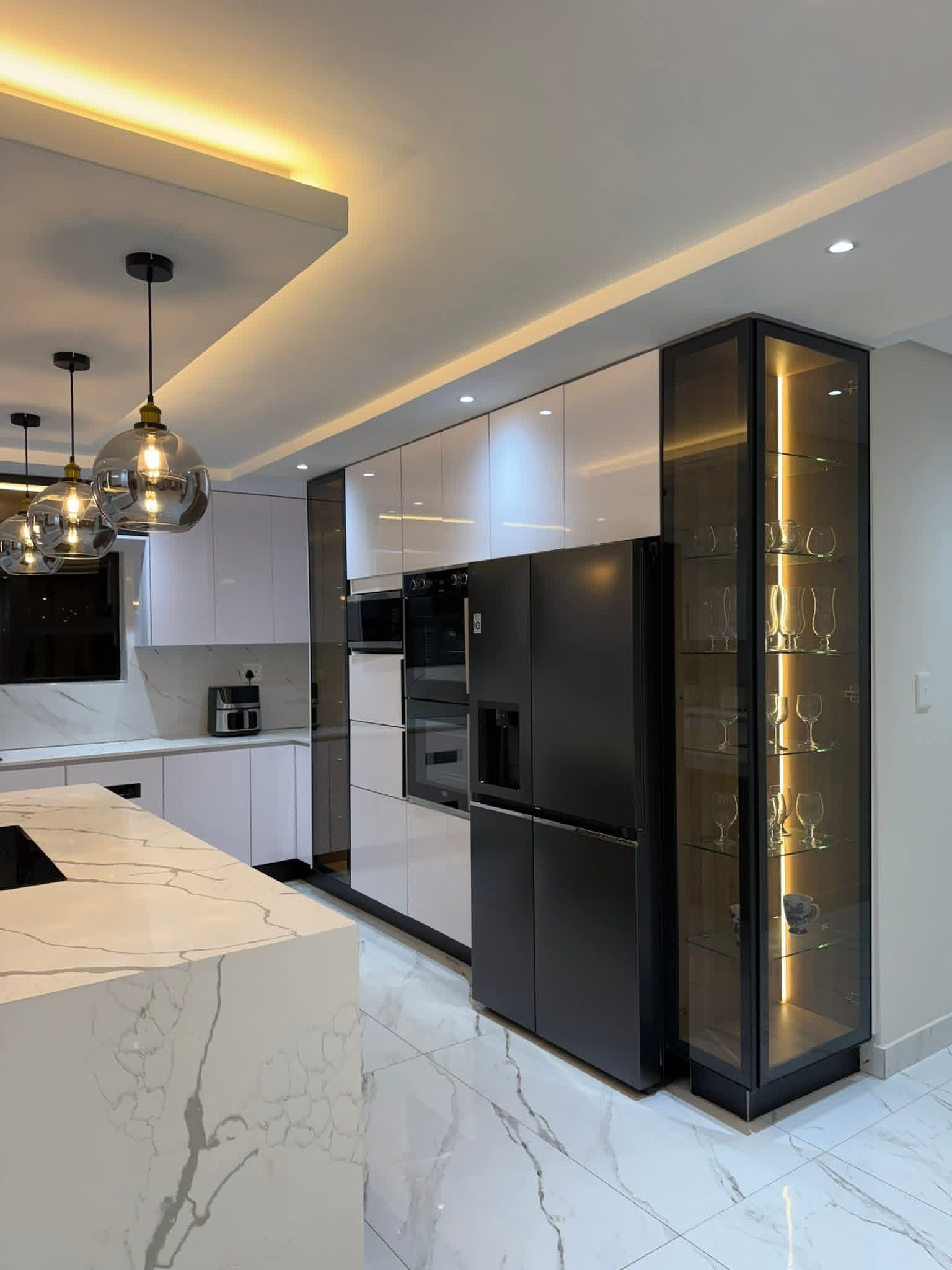 Full-height smoked glass display cabinet beside a black American-style fridge freezer