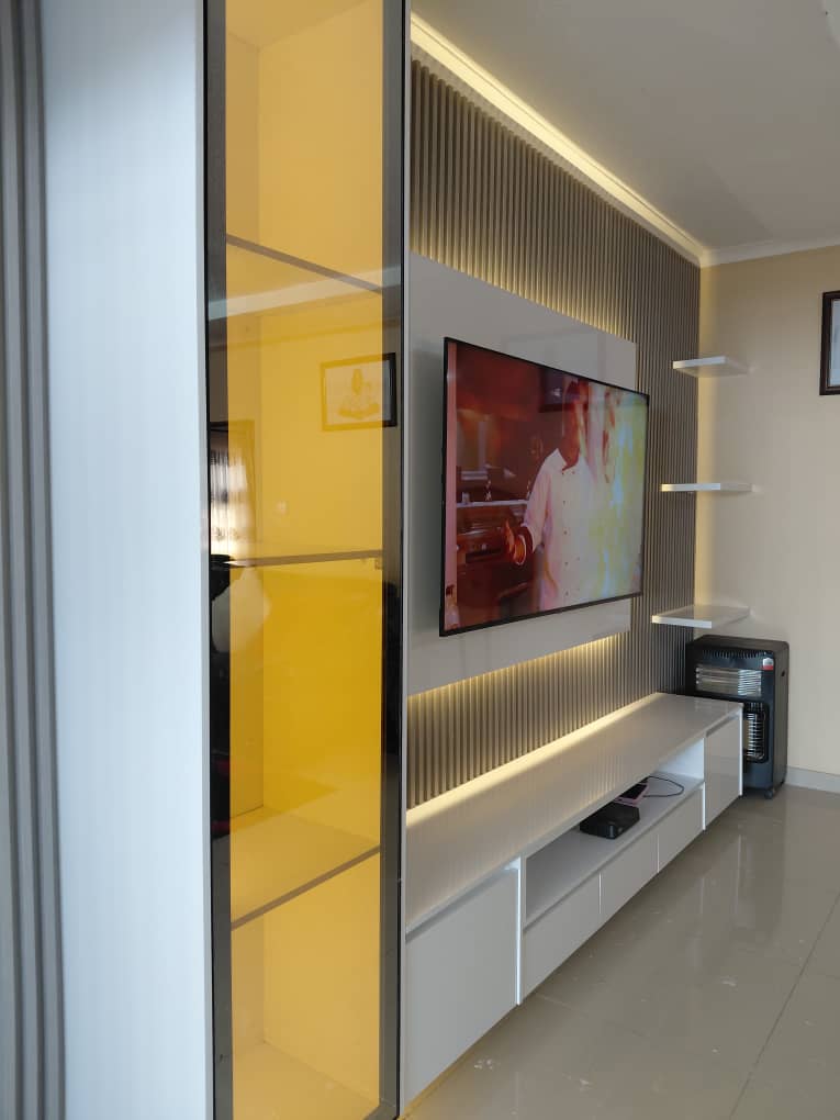 Slim TV unit with amber glass display, fluted backdrop and floating white cabinets