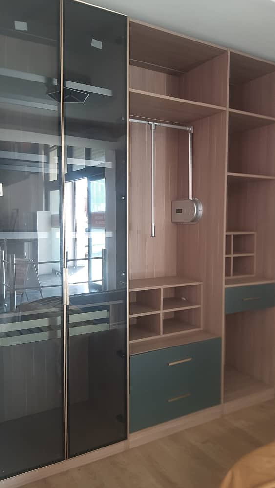 Sliding smoked-glass wardrobe with oak interiors, pull-down hanging rail and teal drawers